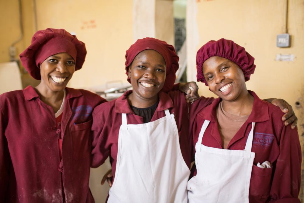 Three women smiling in aprons